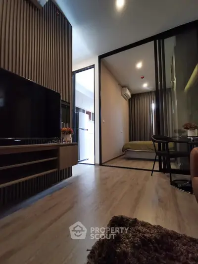 Modern living room with open view to bedroom, featuring sleek design and cozy ambiance.