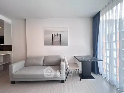 Modern living room with stylish sofa and elegant dining table by large window with sheer curtains.
