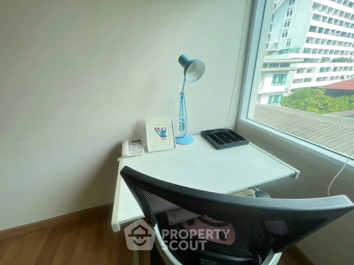 Bright study nook with desk, chair, and window view in modern apartment.