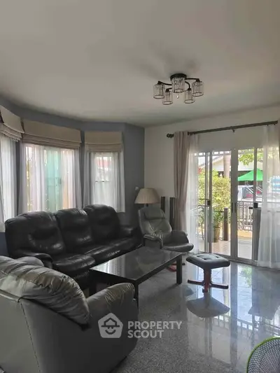 Spacious living room with leather sofas and large windows offering garden view