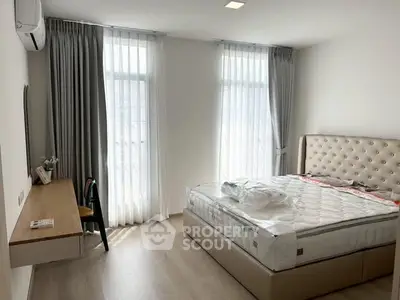 Spacious bedroom with modern decor and large windows for natural light.