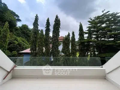 Spacious balcony with lush greenery view and modern glass railing