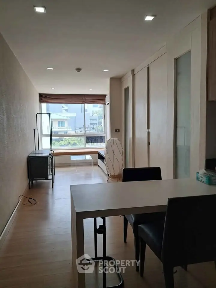 Modern living room with sleek furniture and large window offering natural light and neighborhood view.