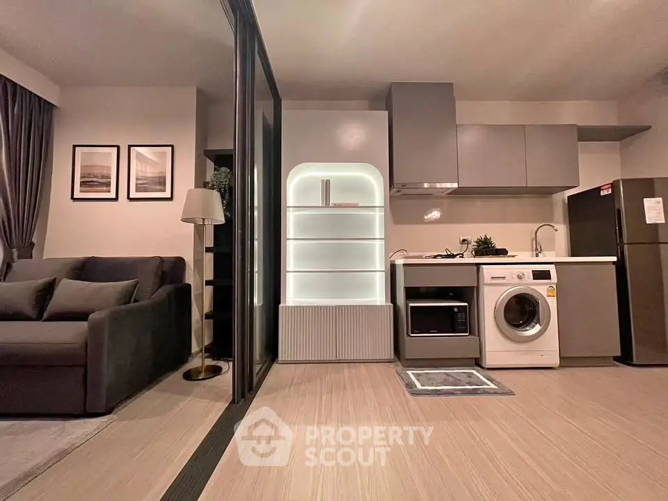 Modern open-layout living room with integrated kitchen featuring sleek appliances and stylish decor.
