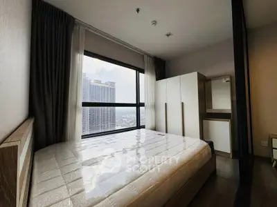 Modern bedroom with large window offering stunning city view and sleek furniture.