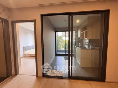 Modern apartment with open kitchen and balcony view, featuring sleek design and ample natural light.