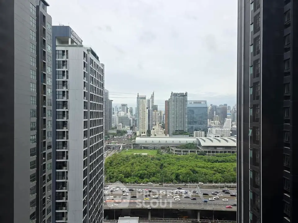 Stunning cityscape view from high-rise building with lush greenery and bustling highway below.