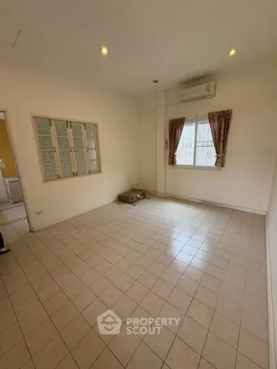 Spacious empty room with tiled floor and window, ideal for customization.