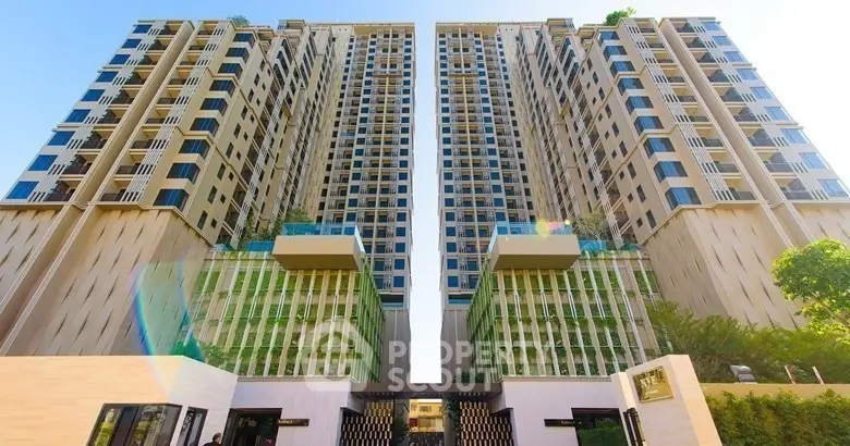 Stunning modern high-rise apartment building with lush greenery and elegant facade.