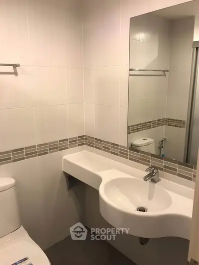 Modern bathroom with sleek white fixtures and large mirror in a contemporary apartment.