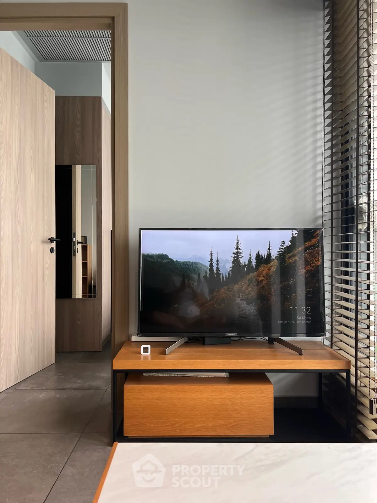 Modern living room with sleek TV setup and stylish wooden furniture, perfect for cozy entertainment.