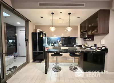 Modern kitchen with sleek black countertops, stainless steel appliances, and stylish bar stools, perfect for entertaining guests in a chic urban condo.