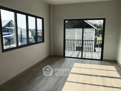 Spacious room with large windows and balcony access, offering ample natural light and modern flooring.
