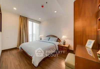 Spacious bedroom with wooden flooring and elegant decor in modern apartment.