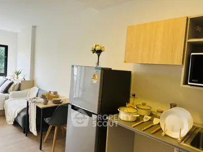 Modern kitchen with sleek appliances and cozy dining area in open layout apartment.