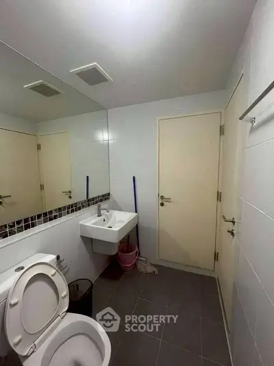 Modern bathroom with sleek fixtures and large mirror in a contemporary apartment.