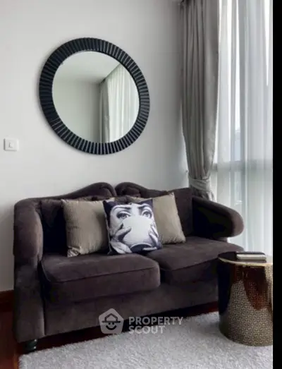 Stylish living room with plush sofa, decorative mirror, and elegant curtains.