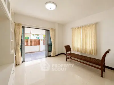 Spacious living room with elegant chaise lounge and large windows opening to a patio.