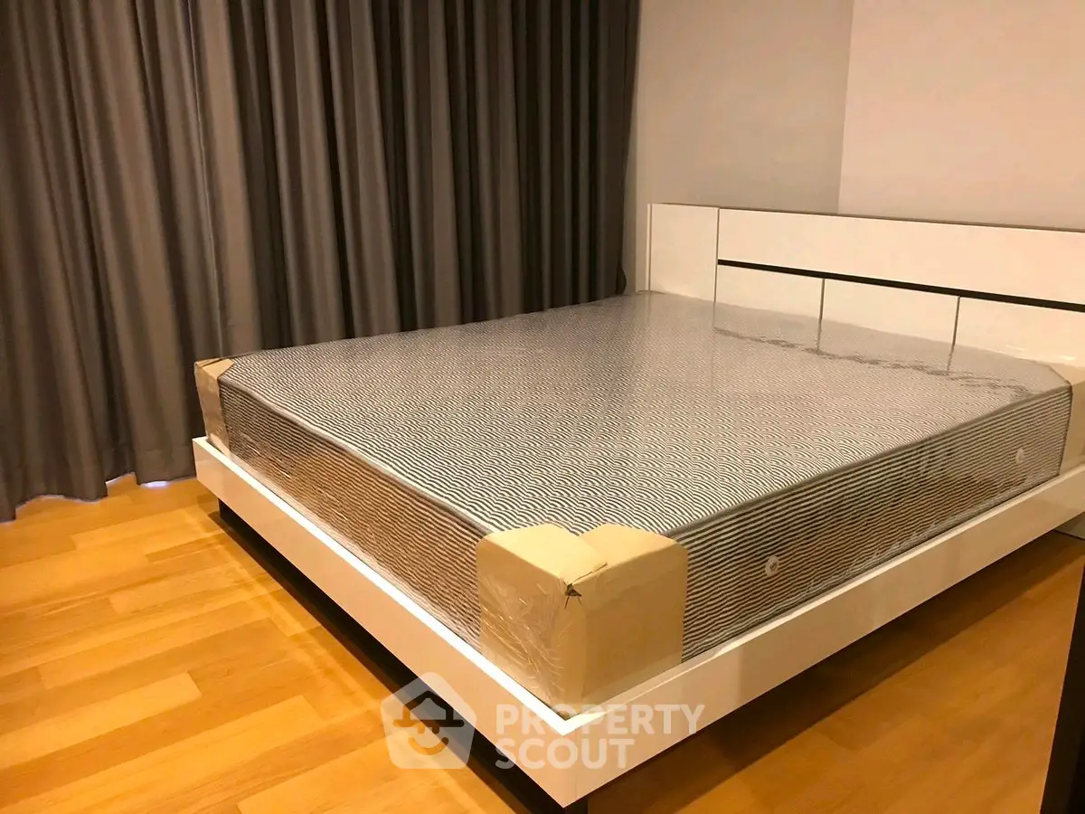 Spacious bedroom with new mattress and elegant wooden flooring.