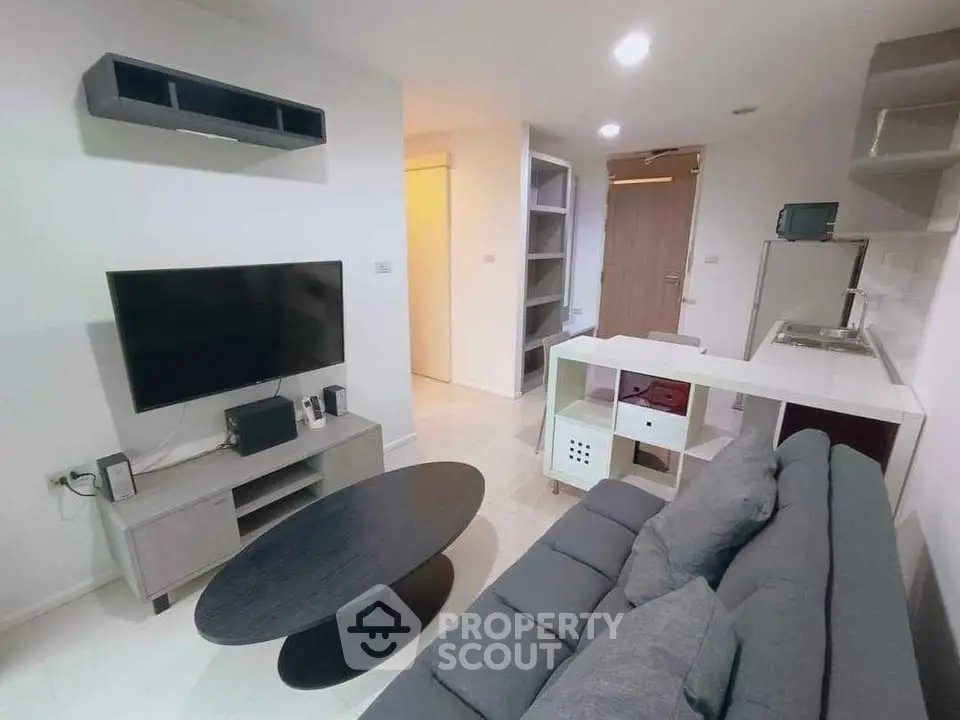 Modern living room with sleek furniture and wall-mounted TV in a cozy apartment.