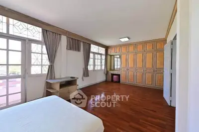 Spacious bedroom with wooden flooring and ample natural light