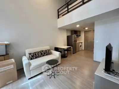 Modern loft apartment with open living area, stylish furniture, and compact kitchen.