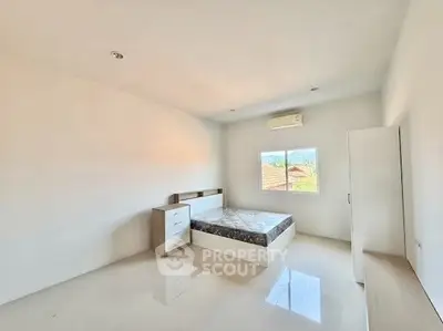Spacious minimalist bedroom with natural light and scenic view, featuring modern furniture and air conditioning.