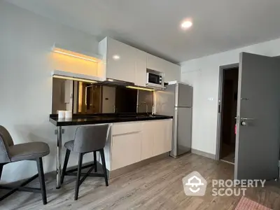 Modern kitchen with sleek cabinets and stainless steel appliances in a cozy apartment.