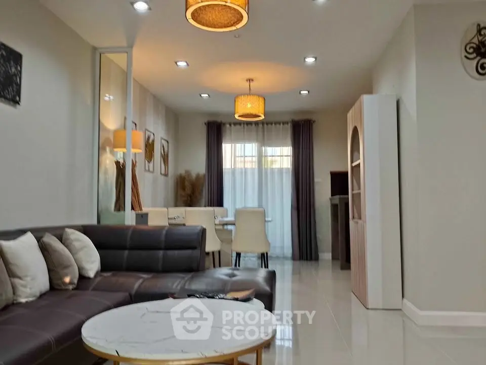 Modern living room with elegant decor and dining area, featuring stylish lighting and cozy seating.