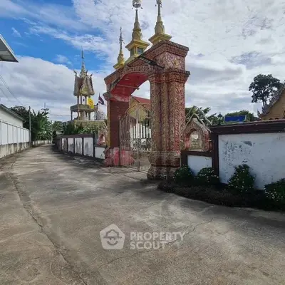 Stunning ornate entrance gate with intricate designs leading to a serene property, showcasing cultural architecture.