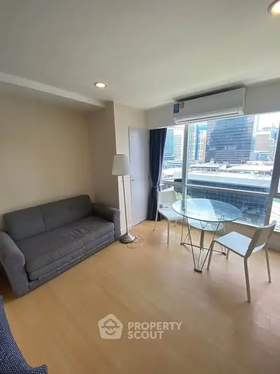 Modern living room with city view, featuring a cozy sofa and dining area, perfect for urban living.
