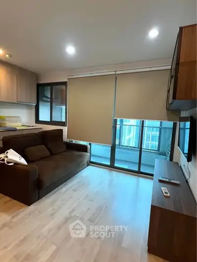 Modern living room with sleek furniture and large window overlooking cityscape.