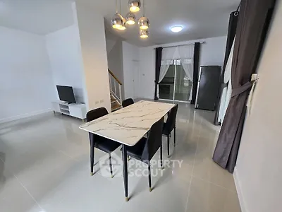Modern dining area with marble table and sleek black chairs in a stylish open-plan living space.