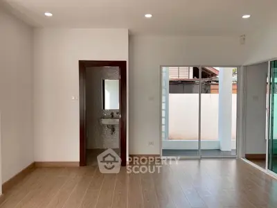Spacious modern living room with wooden flooring and sliding glass doors leading to a private outdoor area.