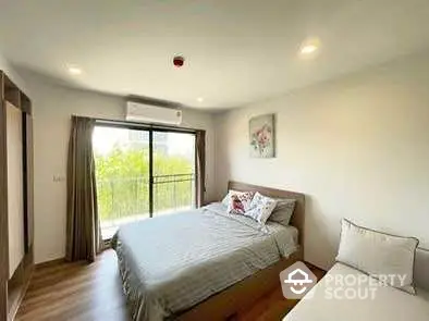 Spacious bedroom with large window and modern decor in a cozy apartment.