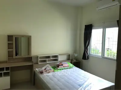 Cozy bedroom with natural light, featuring a comfortable bed and a stylish wooden vanity desk.