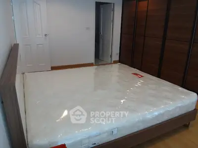 Spacious bedroom with new mattress and wooden wardrobe, ideal for comfort and storage.