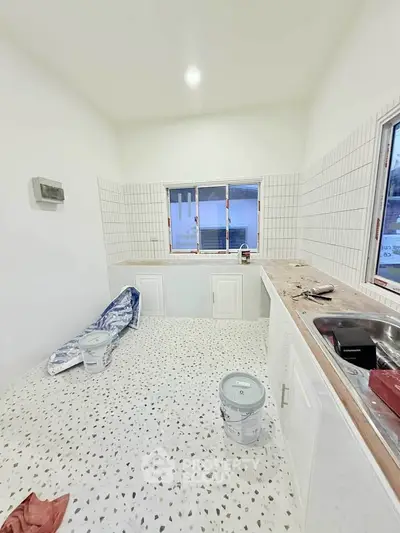 Bright kitchen under renovation with white cabinets and terrazzo flooring