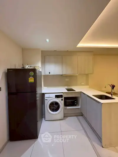 Modern kitchen with sleek appliances and minimalist design, featuring a washing machine and microwave.