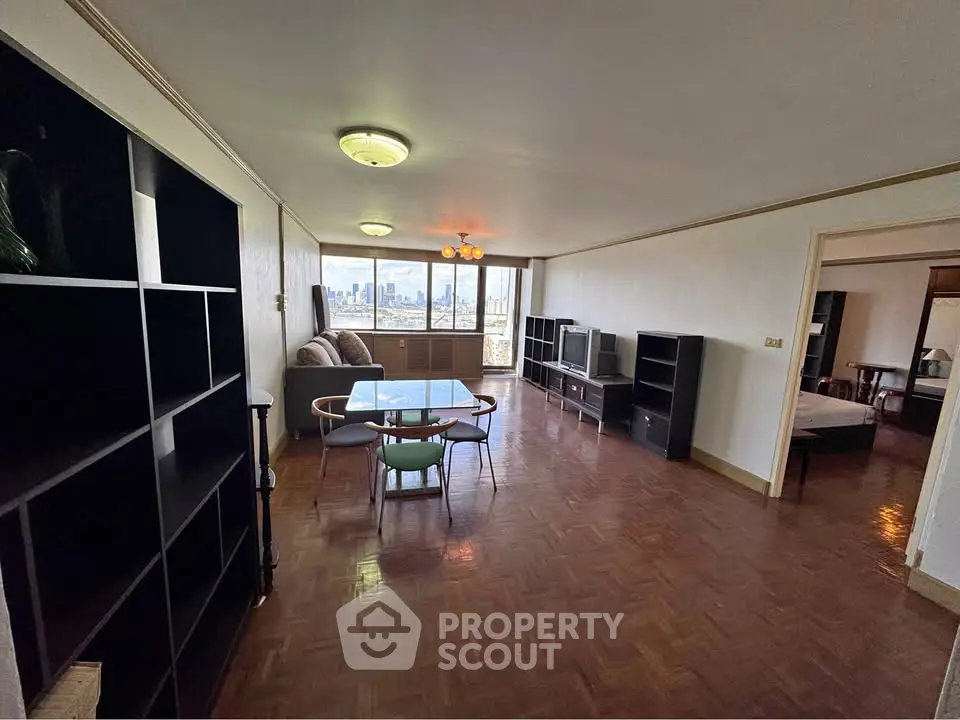 Spacious living room with city view, parquet flooring, and modern furniture in a high-rise apartment.
