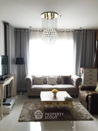 Elegant living room with plush sofa, chic chandelier, and stylish decor for a cozy ambiance.