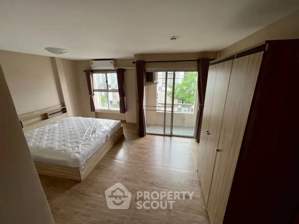 Spacious bedroom with balcony access and modern wooden flooring