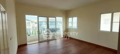 Spacious empty room with large windows and balcony access in modern home.