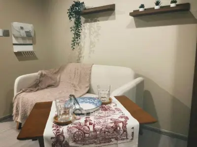 Cozy living room corner with a small sofa, wooden table, and decorative shelves.