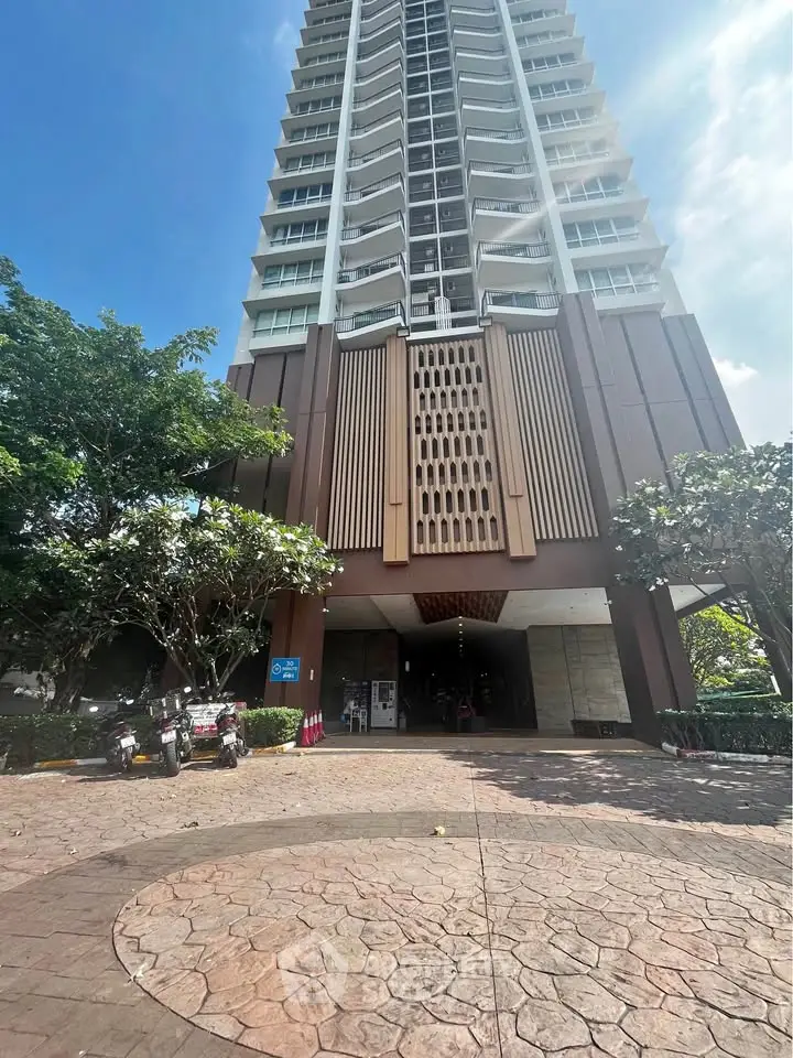 Stunning high-rise building entrance with lush greenery and modern architecture.