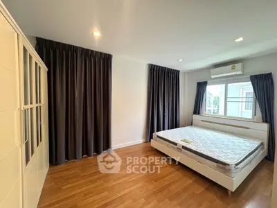Spacious bedroom with wooden flooring and large windows for natural light