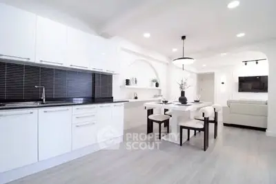 Modern open-plan kitchen and dining area with sleek white cabinetry and stylish decor.
