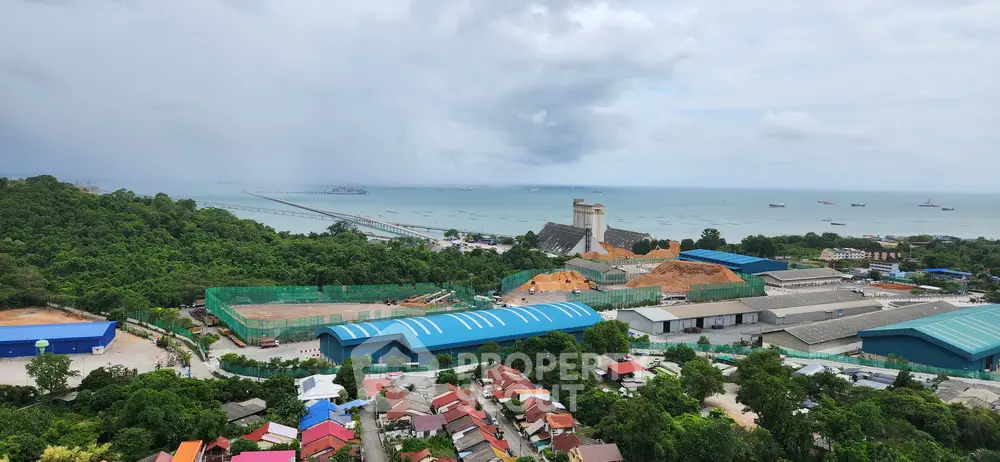 Stunning coastal view with lush greenery and industrial buildings near the ocean, perfect for development.