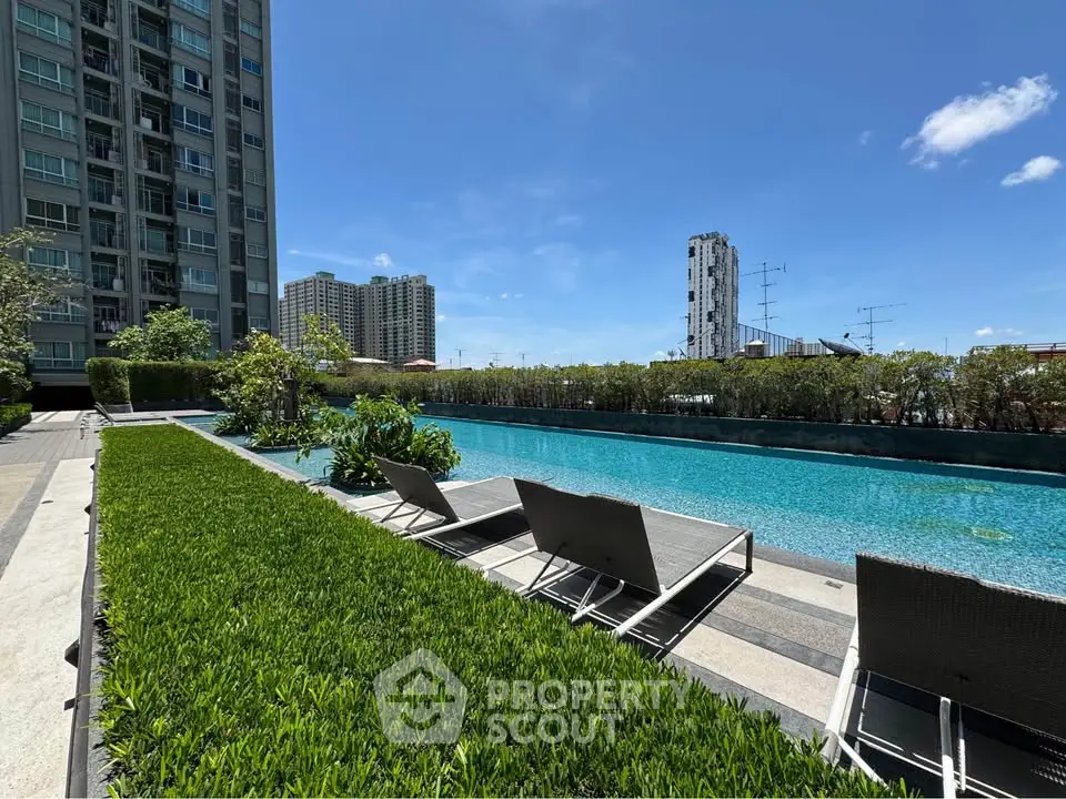 Luxurious apartment complex with stunning pool and lush greenery under clear blue sky.