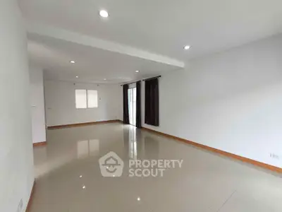 Spacious empty living room with glossy tiled floors and recessed lighting